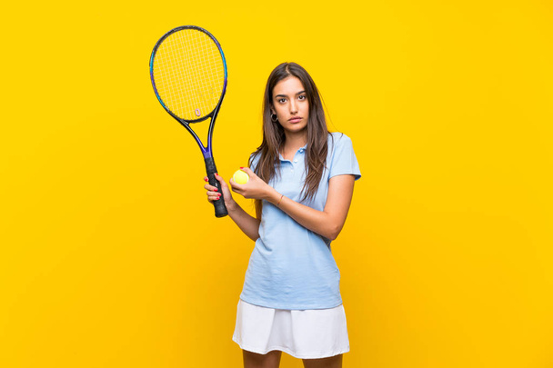 Jonge tennisspeler vrouw over geïsoleerde gele muur - Foto, afbeelding