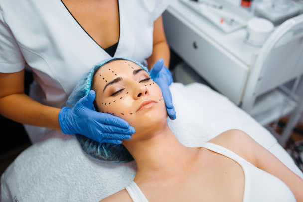 Kozmetikçi kadın hasta yüzünde noktalı çizgiler halinde botoks enjeksiyonu yapar. Botoks enjeksiyonu hazırlar. Güzellik salonunda gençleştirme prosedürü. Kırışıklıklara ve yaşlanmalara karşı estetik ameliyat - Fotoğraf, Görsel