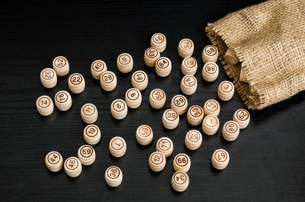 Wooden lotto barrels and bag on a dark wooden table - Φωτογραφία, εικόνα