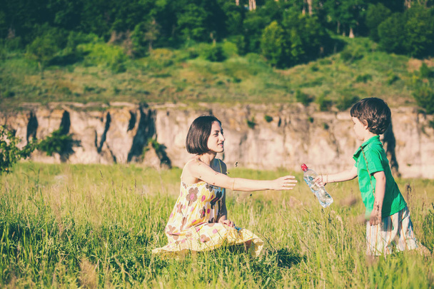 Uma mulher dá à criança uma garrafa de água
. - Foto, Imagem