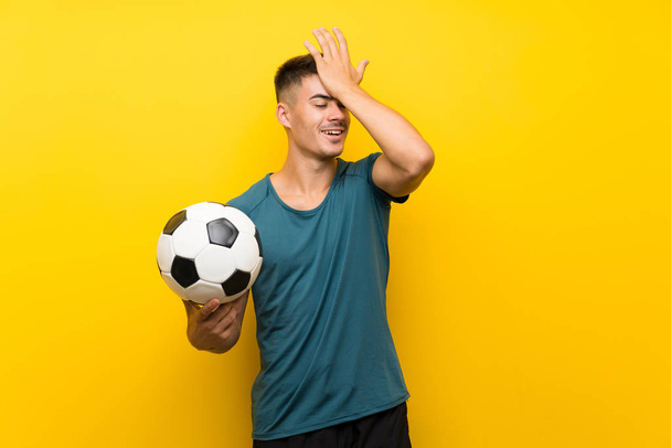 Fešák mladý fotbalista muž přes izolované žluté pozadí si uvědomil něco a záměrem řešení - Fotografie, Obrázek