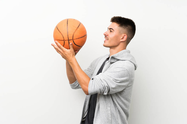 Sport man over geïsoleerde witte muur met bal van basketbal - Foto, afbeelding