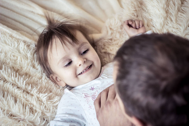 Dad plays with the baby in bed - Foto, Imagen