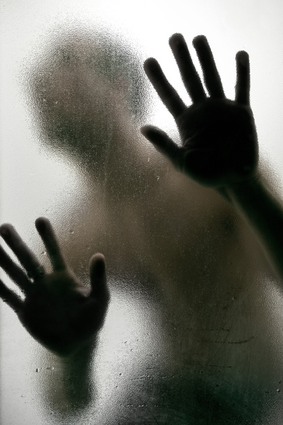 σιλουέτα ενός ανθρώπου με τα χέρια σε ένα παγωμένο ποτήρι - Φωτογραφία, εικόνα