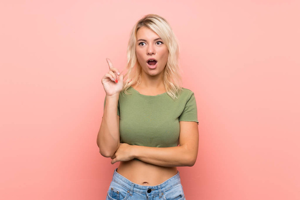 Young blonde woman over isolated pink background thinking an idea pointing the finger up - Photo, image