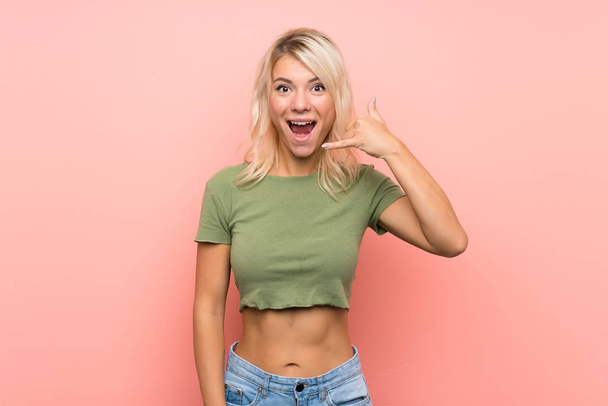 Young blonde woman over isolated pink background making phone gesture. Call me back sign - Photo, Image