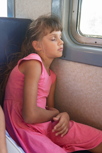 Κουρασμένο κορίτσι αποκοιμήθηκε σε ένα ηλεκτρικό τρένο. - Φωτογραφία, εικόνα
