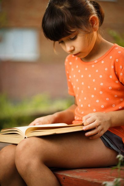 Söpö tyttö lukee ulkona aurinkoisena päivänä, kansainvälinen lukutaito päivä
. - Valokuva, kuva