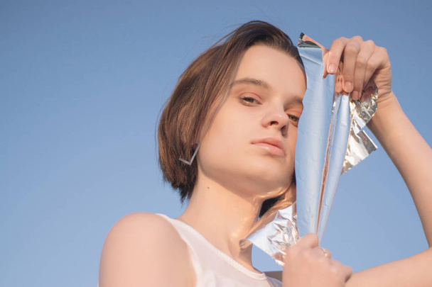 Fashion photo session of a young beautiful woman with foil on sunrise.Vogue style concept - Foto, Bild