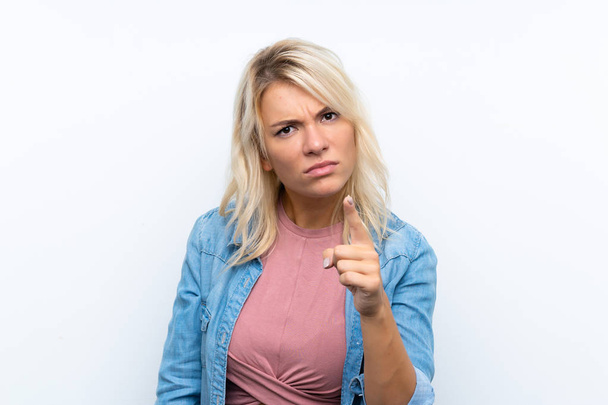 Jeune femme blonde sur fond blanc isolé frustré et pointant vers le devant
 - Photo, image