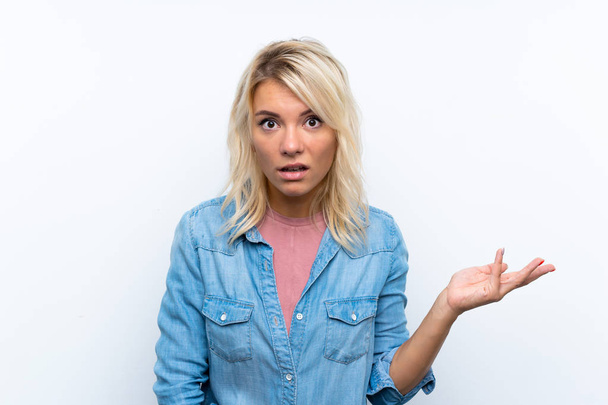 Young blonde woman over isolated white background making doubts gesture - Foto, afbeelding