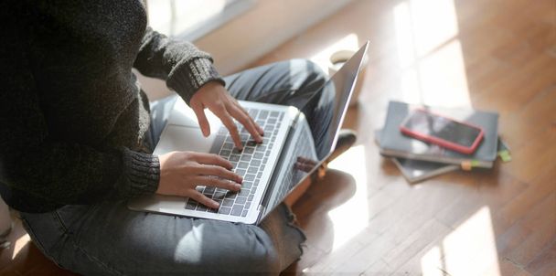 Close-up zicht van jonge vrouwelijke freelancer werken aan haar project met laptop computer terwijl zitten in de buurt van de ramen  - Foto, afbeelding