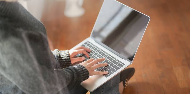 Colpo ritagliato di giovane freelance donna che digita sul computer portatile mentre lavora al suo progetto e seduto accanto alle finestre
  - Foto, immagini