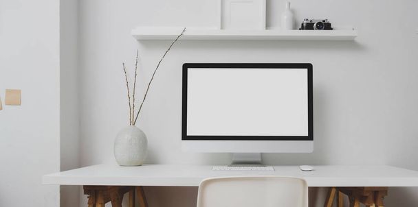 Spazio di lavoro moderno con computer desktop a schermo vuoto e decorazioni su tavolo bianco e sfondo bianco della parete
  - Foto, immagini
