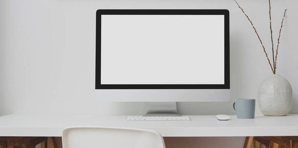 moderner Arbeitsplatz mit leerem Bildschirm Desktop-Computer und Dekorationen auf weißem Tisch und weißem Wandhintergrund  - Foto, Bild