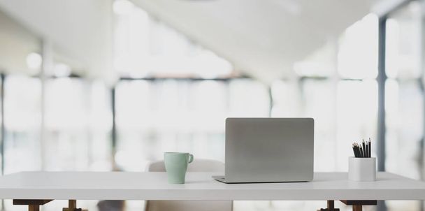 Computer portatile su tavolo bianco e tazza di caffè in ufficio moderno con sfondo sfocato
  - Foto, immagini