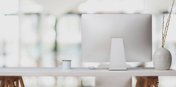 Ordenador de sobremesa sobre mesa blanca y taza de café en moderna sala de oficina con fondo borroso
  - Foto, Imagen