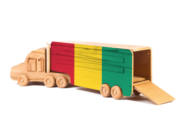 Közelkép egy fából készült játékautóról festett nemzeti zászlóval Guineában. Az export-import, a szállítás, a nemzeti áruszállítás fogalma  - Fotó, kép