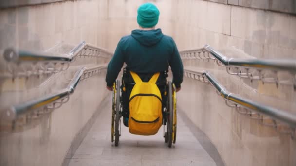 Niepełnosprawny mężczyzna na wózku inwalidzkim schodzi z długiej rampy - Materiał filmowy, wideo