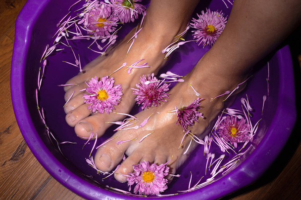 piękno kobiece nogi w kąpieli z kwiatami, aromatyczne spa z ziołami leczniczymi - Zdjęcie, obraz