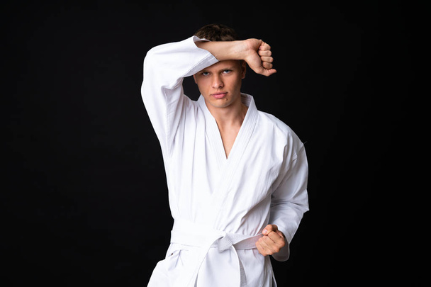 Young man doing karate over isolated black background - Фото, зображення