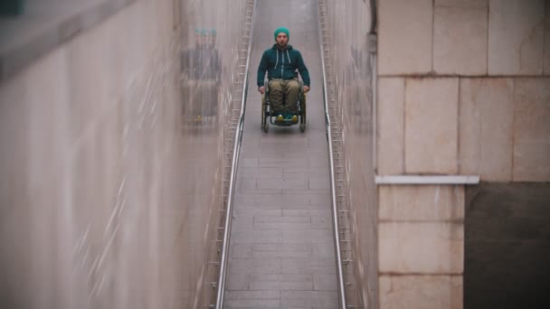 Disabled man in wheelchair riding downward the long special ramp - Footage, Video