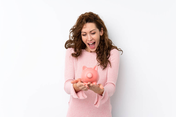 Young pretty woman over isolated background holding a big piggybank - Photo, Image