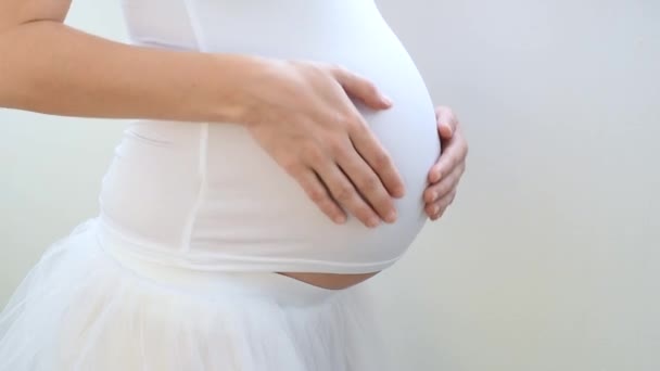 close-up van een zwanger jong meisje strelen haar buik met een baby binnen - Video