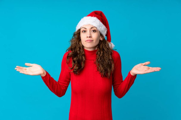 Mädchen mit Weihnachtsmütze über gelbem Hintergrund hat Zweifel mit verwirrtem Gesichtsausdruck - Foto, Bild