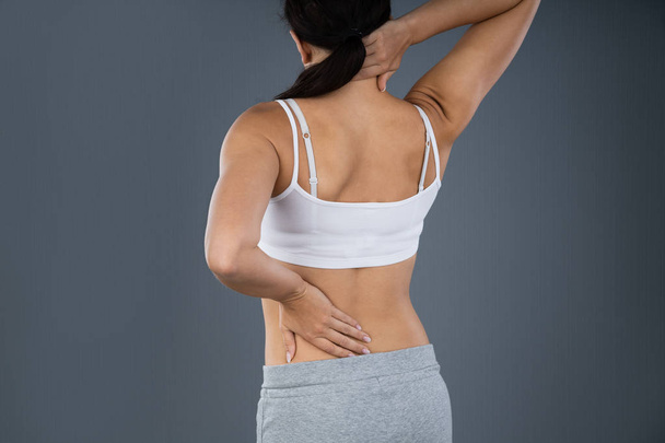 Woman Suffering From Back Pain Over Gray Background - Фото, изображение