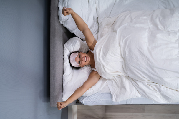 Γυναίκα χαμογελά ενώ ξυπνάει από το κρεβάτι - Φωτογραφία, εικόνα