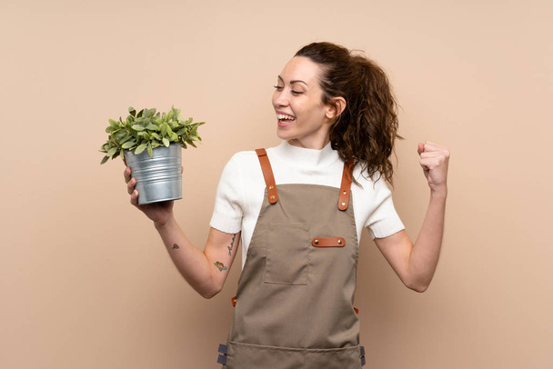 Mujer jardinero sosteniendo una planta celebrando una victoria
 - Foto, Imagen