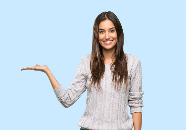 jonge hispanic brunette vrouw houden copyspace imaginaire op de palm om een advertentie in te voegen over geïsoleerde achtergrond - Foto, afbeelding