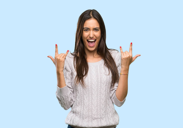Молодая латиноамериканка-брюнетка делает рок-жест на изолированном фоне
 - Фото, изображение