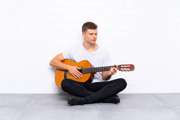 Jonge knappe man met gitaar - Foto, afbeelding