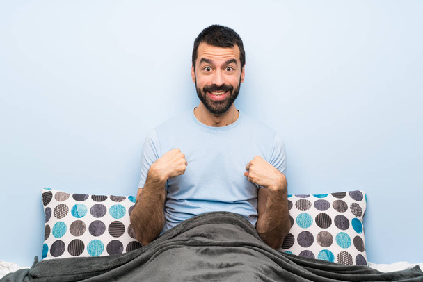Uomo a letto con espressione facciale a sorpresa
 - Foto, immagini