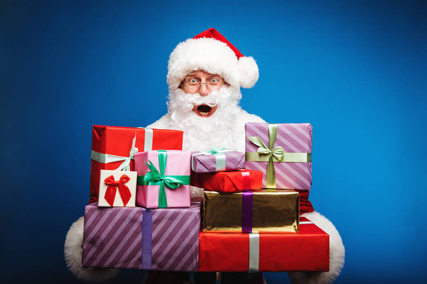  Christmas and New year concept.  Portrait of man in Santa Clause costume with gifts - 写真・画像