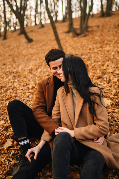 Stylish young couple outdoors on a beautiful autumn day in the forest. Young couple in love holding hands and walking through a park on a autumn day. The concept of youth, love and lifestyle. - Fotoğraf, Görsel