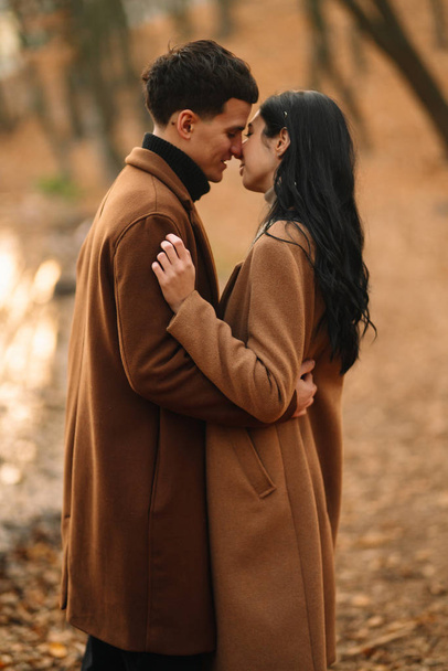Elegante jovem casal ao ar livre em um belo dia de outono na floresta. Jovem casal apaixonado de mãos dadas e caminhando por um parque em um dia de outono. O conceito de juventude, amor e estilo de vida
. - Foto, Imagem