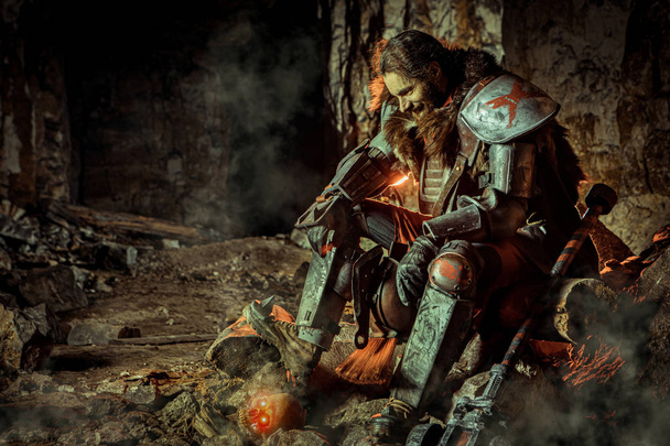 ハンマーで鎧の強力な騎士が石の上に座っています。背景にダンジョン. - 写真・画像