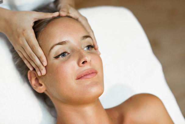 Young woman receiving a head massage in a spa center. - Fotoğraf, Görsel