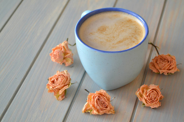 filiżanka kawy i suche kwiaty róży w kolorze kremowym na niebieskim stole vintage, styl prowansji - Zdjęcie, obraz