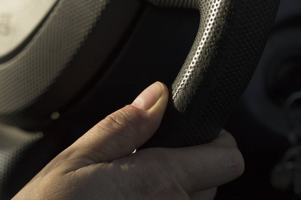 The girl's hand holds the steering wheel of the car during traffic. A female motorist. - Photo, image