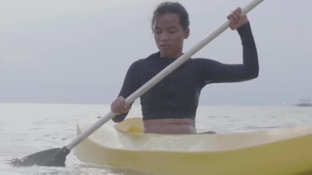 Close up shot of a young woman paddling on kayak boat in the ocean at sunny day - 映像、動画