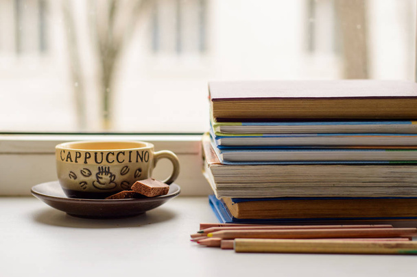 ochtend student: Cup cappuccino koffie, chocolade, boeken en pen - Foto, afbeelding