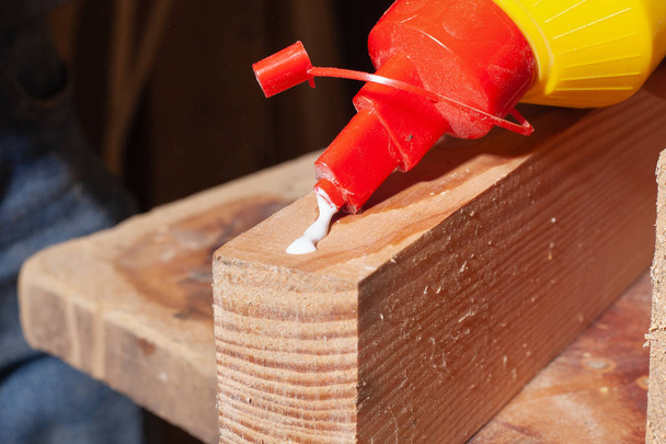 склеивание деревянных изделий, рабочий наклеивает клей на деревянную доску мебели
 - Фото, изображение
