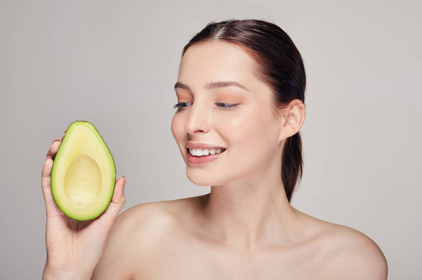 attractive happy and cheerful brown-haired nude lady with perfect pure shine skin with avocado in the right hand - 写真・画像