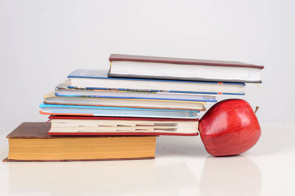 bunte Bücher in der Nähe reifer Apfel auf Tisch auf weißem Hintergrund - Foto, Bild