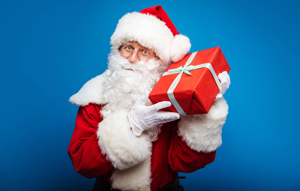  Christmas and New year concept.  Portrait of man in Santa Clause costume with present - Photo, Image