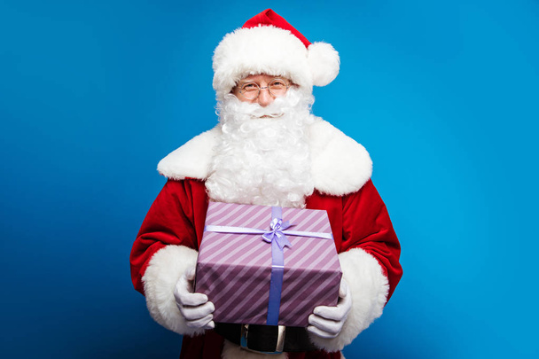  Christmas and New year concept.  Portrait of man in Santa Clause costume with present - Φωτογραφία, εικόνα